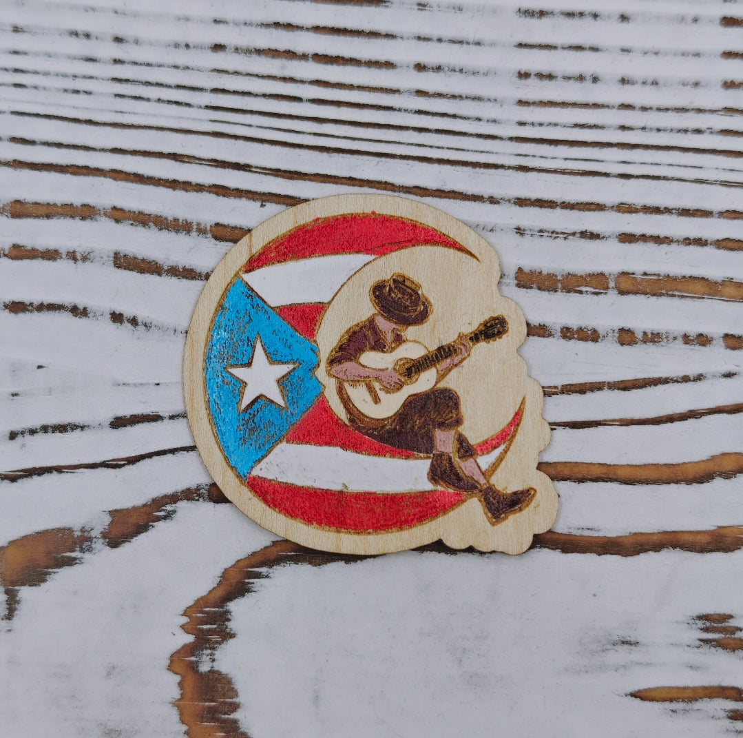 Sticker de madera de arce inspirado en el poema "Boricua en la Luna", con ilustración de un músico tocando guitarra sobre la bandera de Puerto Rico, pintado a mano.