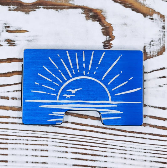 Cartera minimalista azul con diseño de atardecer, sol y aves grabado en metal