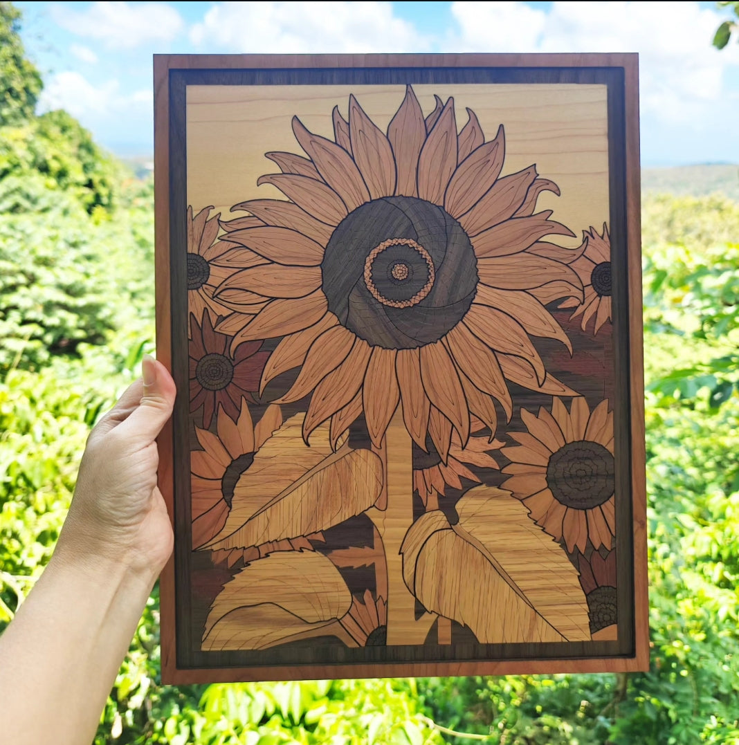 Cuadro de Girasoles hecho con 7 maderas, tamaño 13x10 pulgadas, sostenido a mano frente a paisaje de Puerto Rico