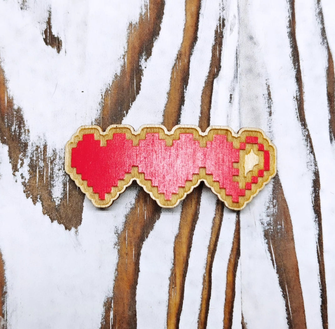 Pixelated heart-shaped object on a wooden surface with white paint strokes