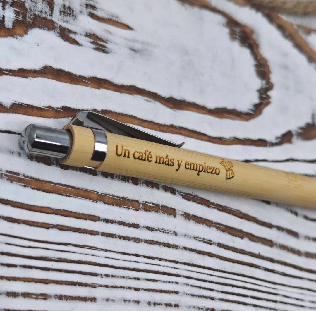 Detalle del grabado láser en bolígrafo de bambú con la frase "Un café más y empiezo" y cafetera
