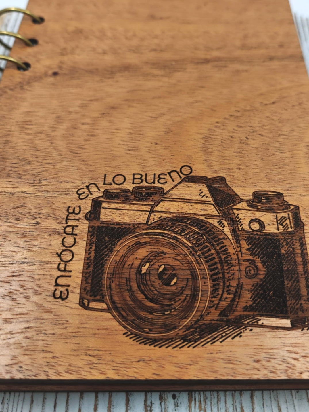 Detalle de la portada de caoba con cámara vintage grabada a mano.
