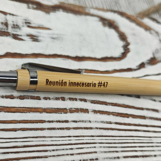 Detalle del grabado láser en bolígrafo de bambú con la frase "Reunión innecesaria #47"