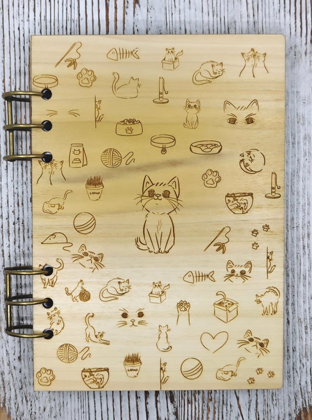 Libreta A5 de madera con iconos de gatos: patitas, ovillos, collares y gatito sentado al centro