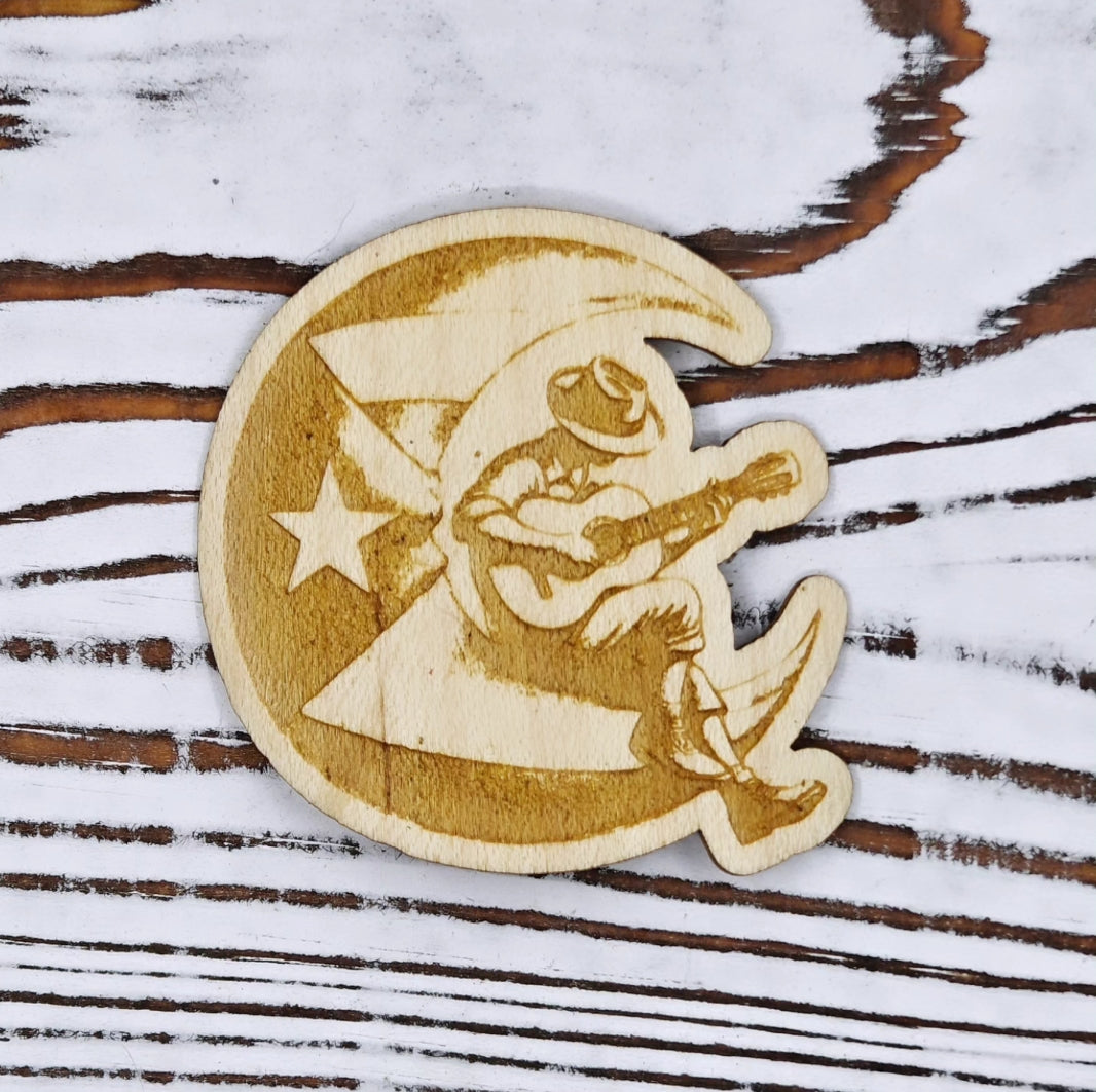 Sticker de madera de arce inspirado en el poema "Boricua en la Luna", con ilustración de un músico tocando guitarra sobre la bandera de Puerto Rico